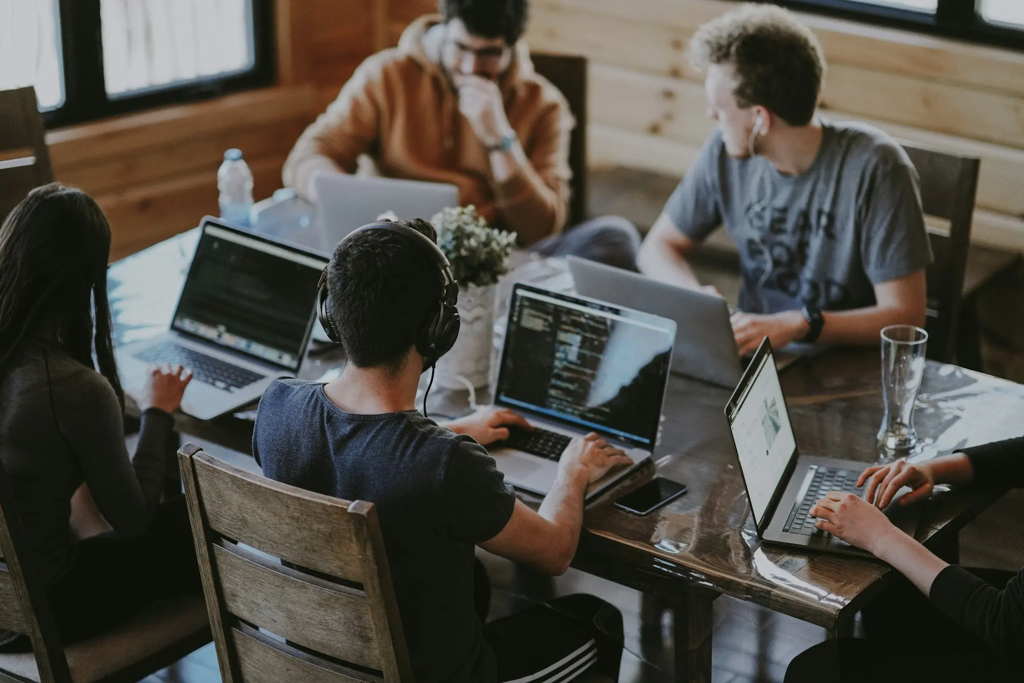 A small team working together on laptops around a wooden table.